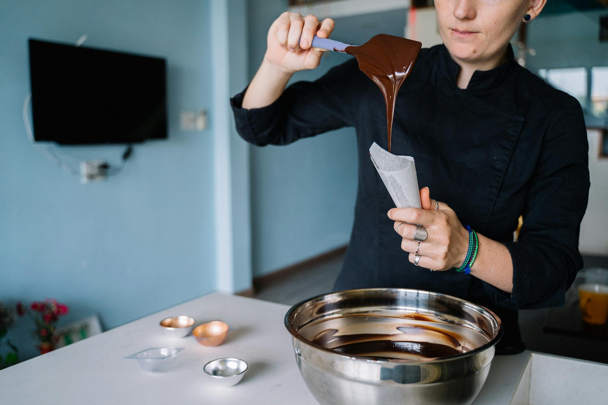 Close-up of a woman chef preparing chocolate with a piping bag indoors.